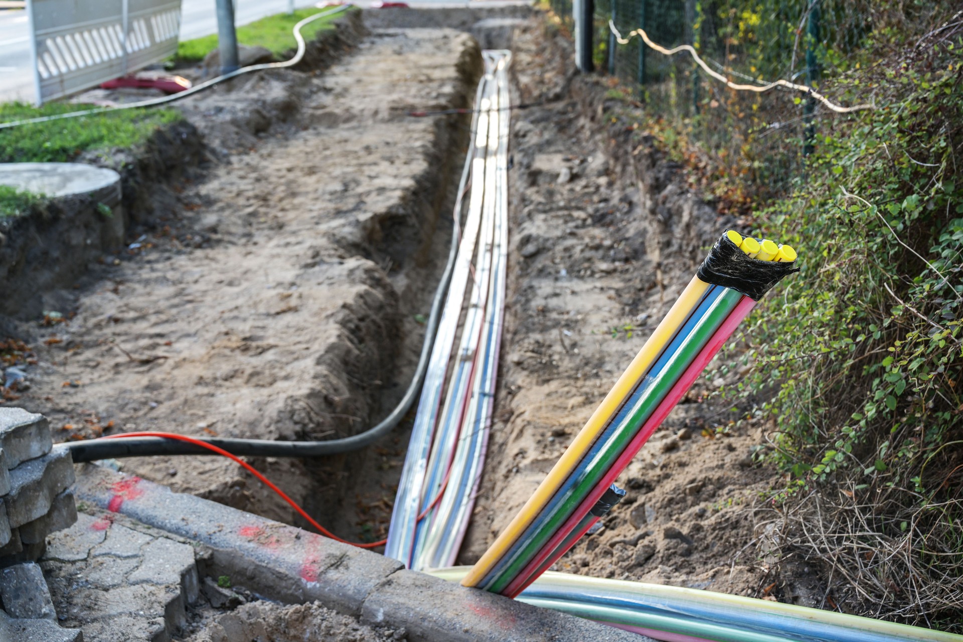 Construction site for installing fiber optic cables under the ground beside a street to bring fast internet to all residents, selected focus